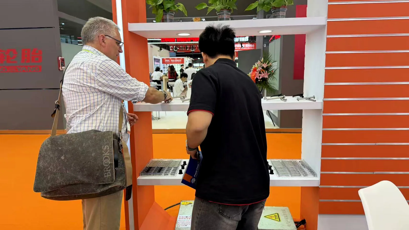 PremFixer staff reviewing displayed bicycle hardware with a booth visitor