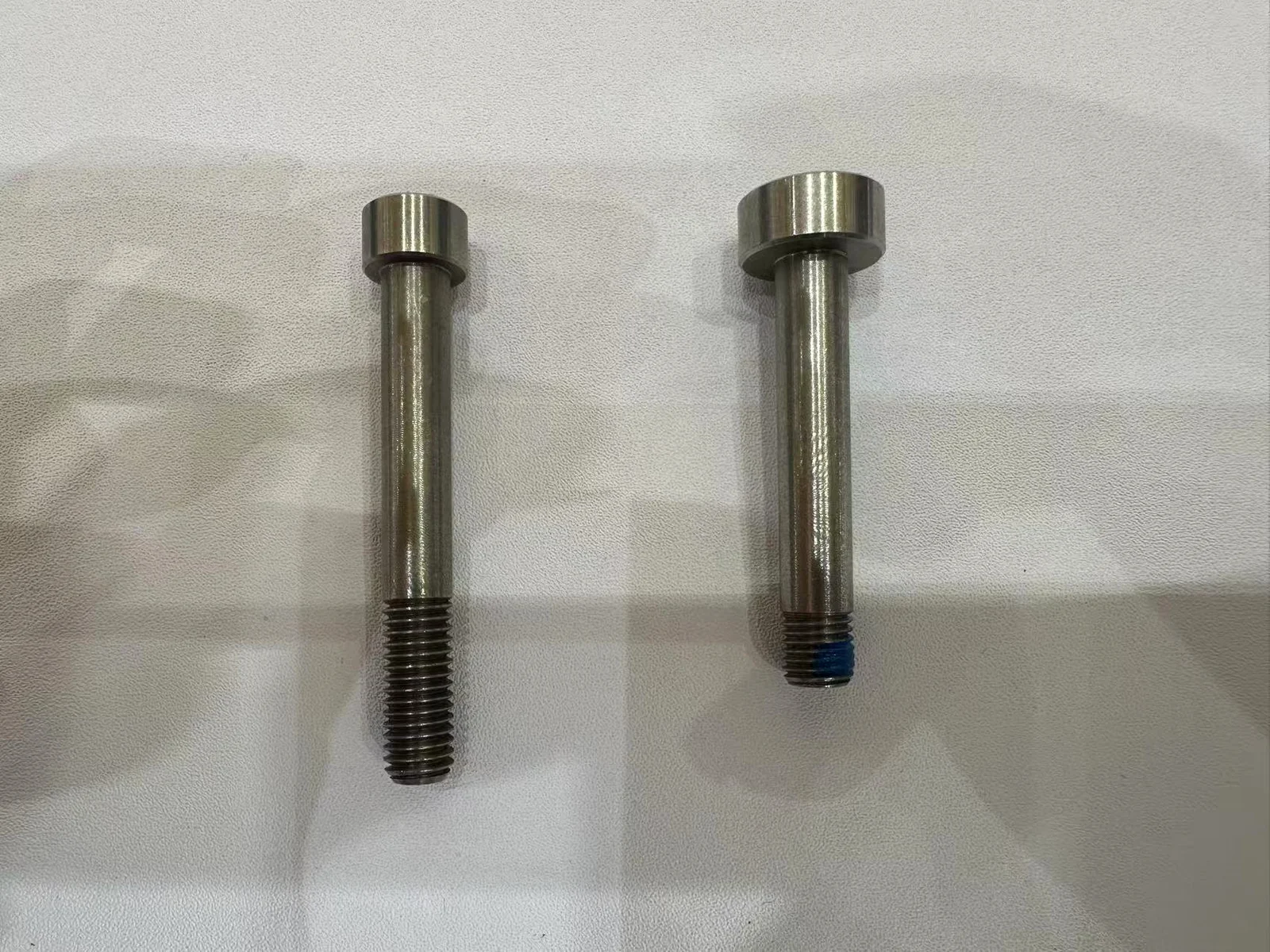Two similar-size stainless bicycle pivot bolt samples for dimensional comparison